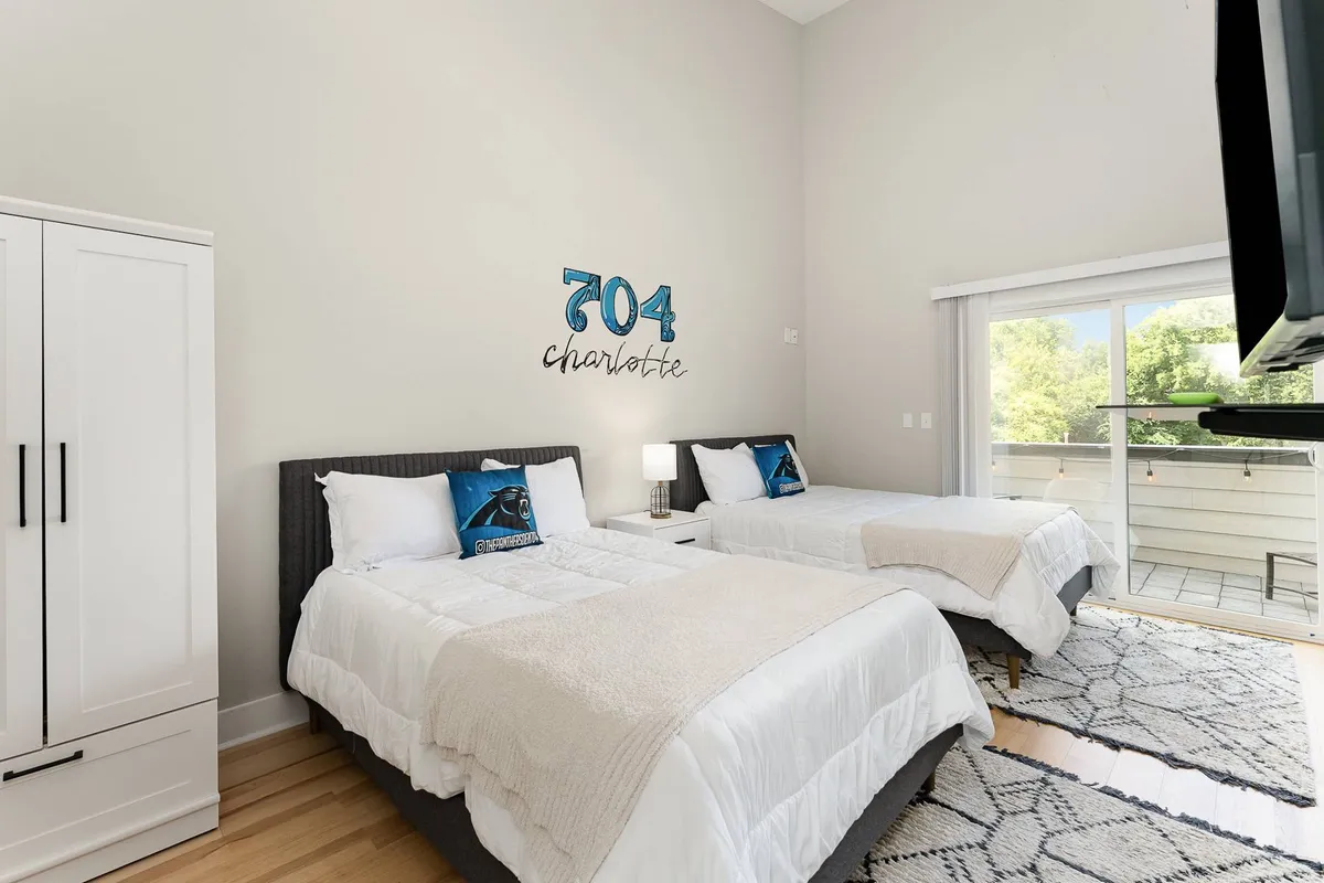 The loft area is shown with two twin beds, decorative wall art, and a view leading to the balcony. Natural light floods the space, highlighting the inviting atmosphere and direct access to the private outdoor area.