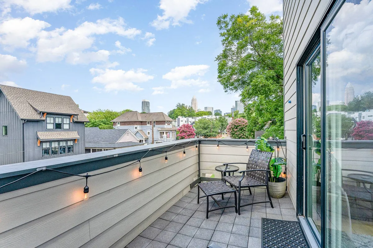 An inviting balcony setting with comfortable seating, decorative plants, and a breathtaking view of the Uptown Charlotte skyline. The atmosphere is serene and welcoming—ideal for relaxing, entertaining, or enjoying morning coffee while immersed in the city buzz.