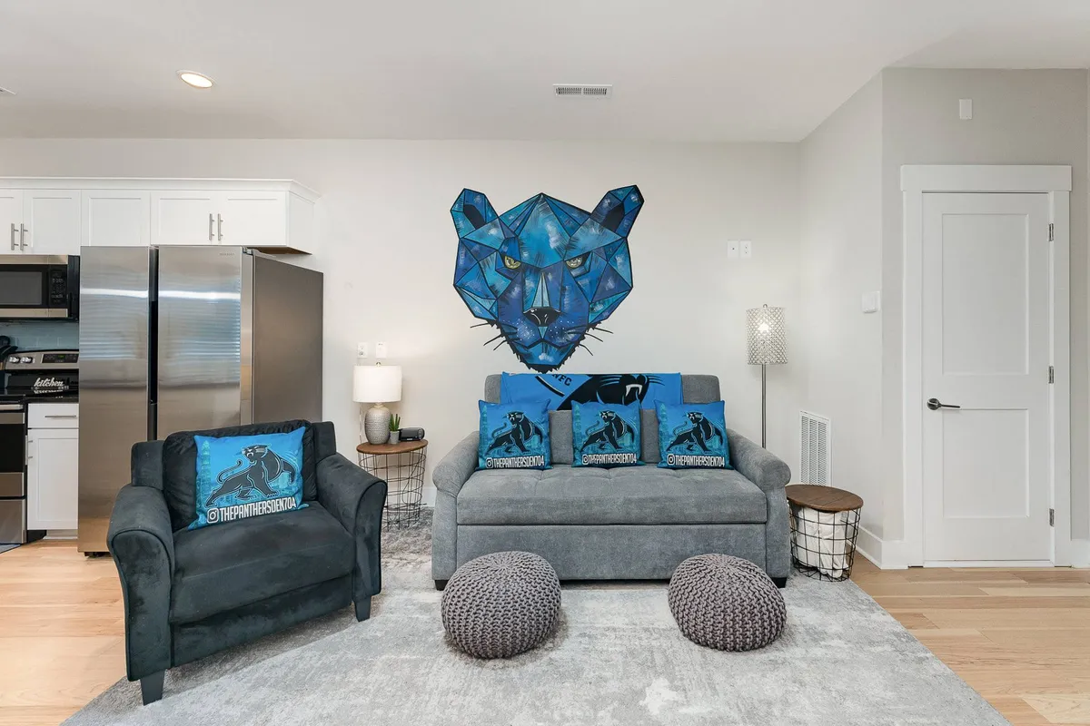 A dynamic living area centered around striking blue panther wall art, surrounded by decorative pillows and textured ottomans. The space feels energetic, perfect for entertaining, relaxing, or hosting game nights with friends.